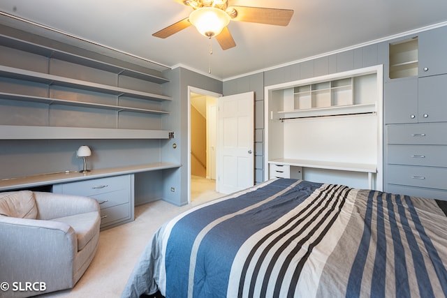 bedroom featuring light carpet, crown molding, built in desk, and ceiling fan