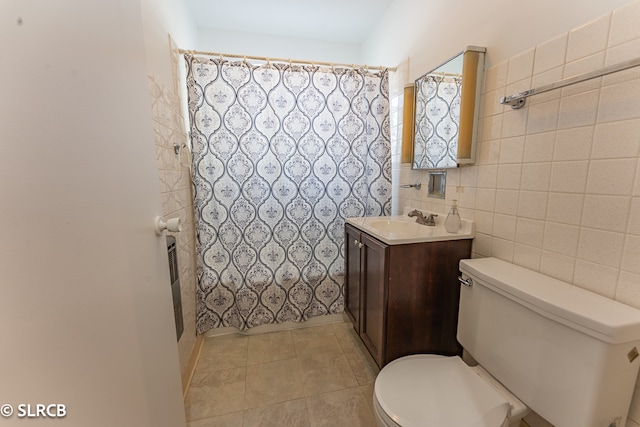 bathroom with tile walls, toilet, vanity, curtained shower, and tile patterned flooring