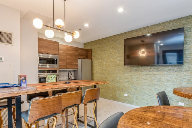 kitchen with butcher block countertops, sink, pendant lighting, and appliances with stainless steel finishes