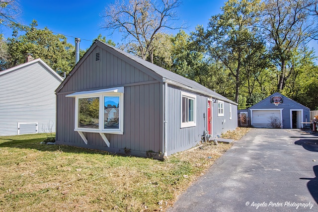 view of property exterior featuring a garage, a yard, and an outbuilding