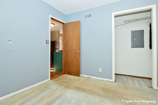 unfurnished bedroom featuring electric panel, a closet, stainless steel refrigerator, and carpet