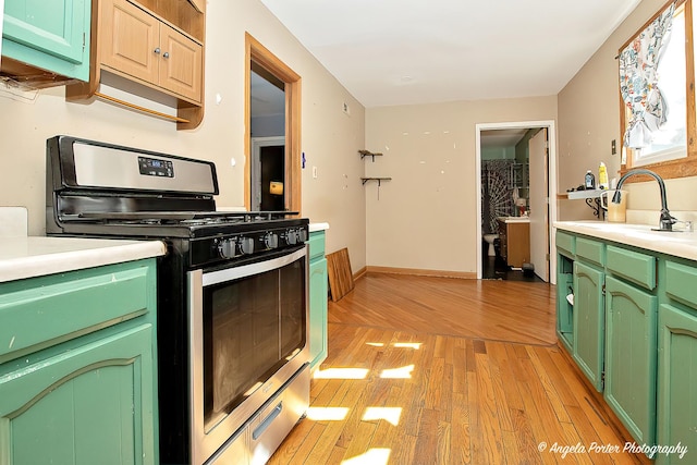 3012 Oakwood Ave, Mchenry, IL 60051 - kitchen with stainless steel range with gas stovetop, a sink, light countertops, green cabinets, and light wood finished floors