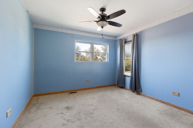 empty room featuring ceiling fan and light colored carpet