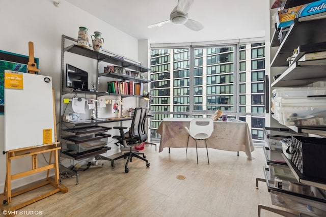 home office featuring hardwood / wood-style flooring, ceiling fan, and expansive windows