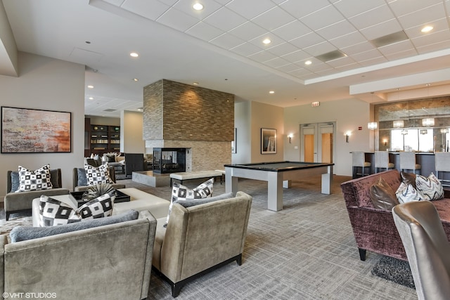 recreation room with a raised ceiling, a multi sided fireplace, billiards, and light carpet