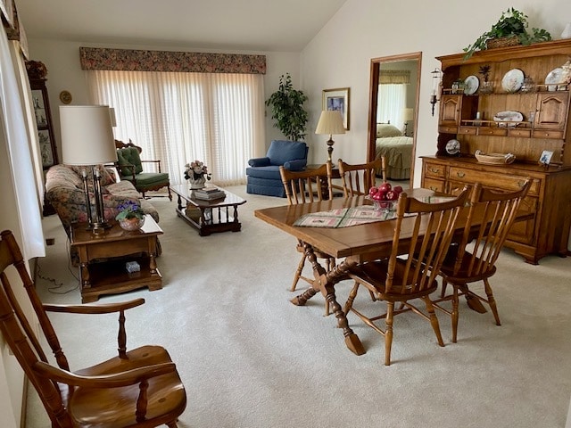 dining room featuring light carpet and lofted ceiling