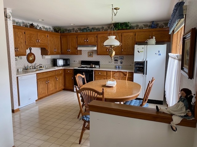 kitchen featuring hanging light fixtures, white appliances, sink, and backsplash