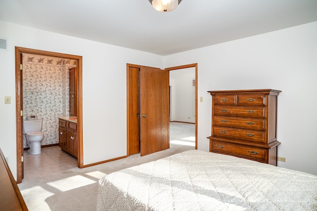 bedroom with light colored carpet and ensuite bathroom