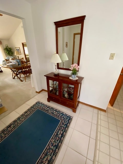 corridor with lofted ceiling and light tile patterned flooring