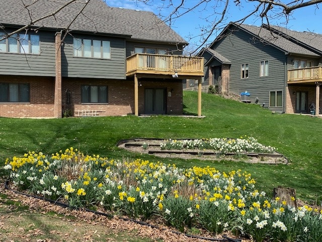 back of property featuring a balcony and a lawn