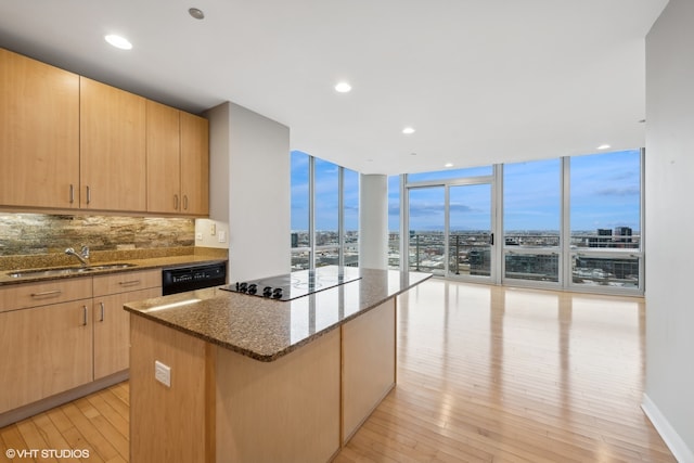 kitchen with black appliances, dark stone countertops, light wood-type flooring, tasteful backsplash, and a kitchen island