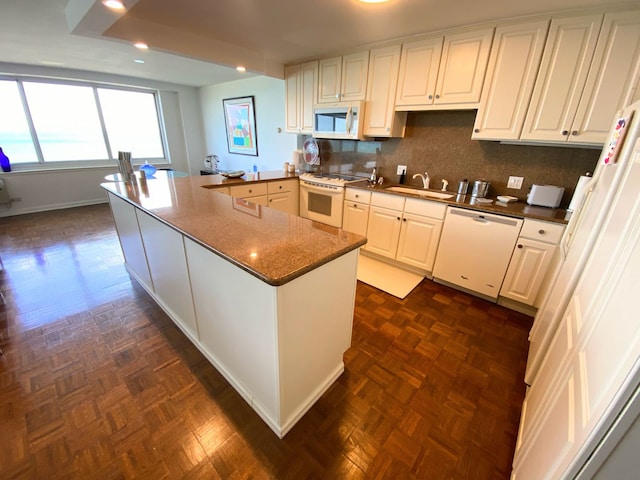 kitchen featuring sink, kitchen peninsula, white appliances, backsplash, and white cabinetry