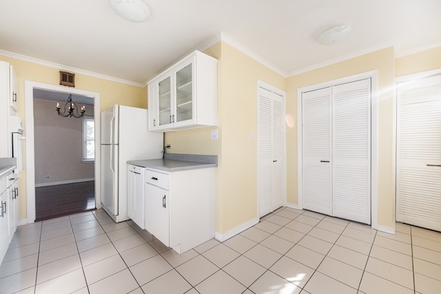 kitchen with white cabinets, white refrigerator, light tile patterned floors, ornamental molding, and a chandelier