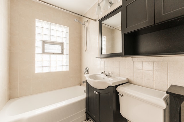 full bathroom with vanity, tile walls, toilet, and tiled shower / bath