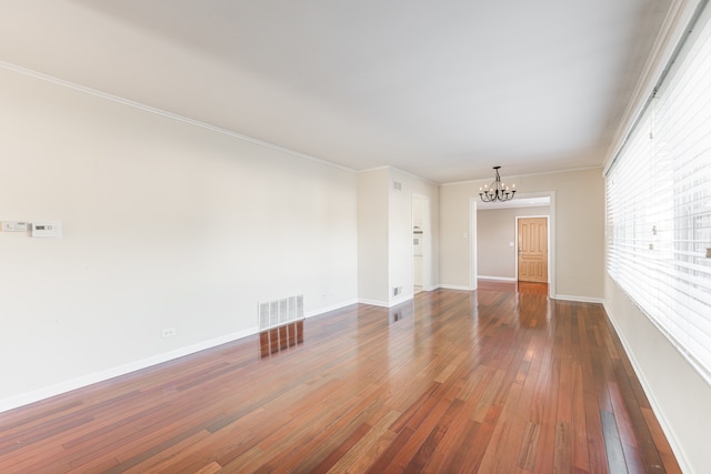 spare room featuring dark hardwood / wood-style floors, a notable chandelier, and ornamental molding