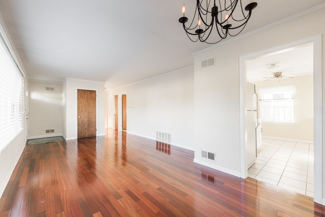 spare room with ceiling fan with notable chandelier, ornamental molding, and hardwood / wood-style floors