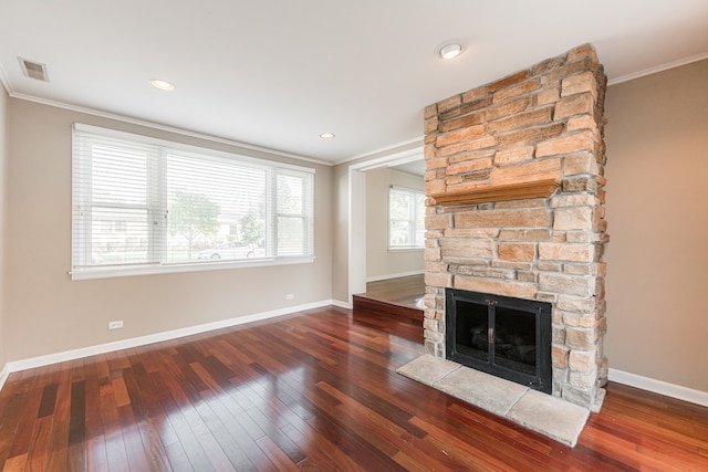 unfurnished living room with a stone fireplace, ornamental molding, and dark hardwood / wood-style flooring