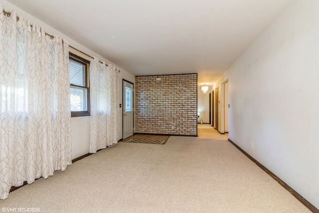 empty room featuring brick wall and light carpet