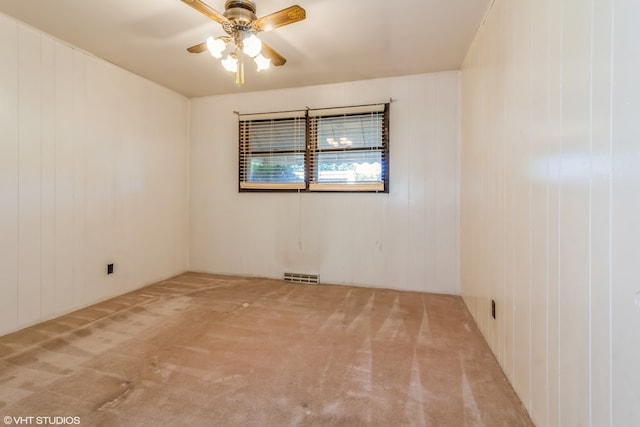 carpeted empty room featuring wood walls and ceiling fan