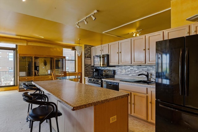 kitchen featuring sink, tasteful backsplash, a center island, black appliances, and a breakfast bar