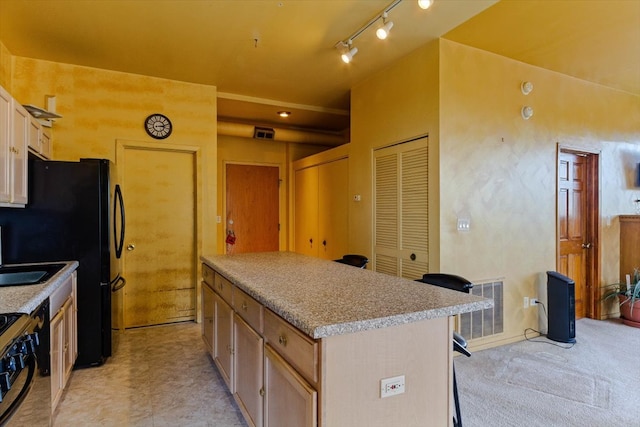 kitchen featuring light brown cabinets, a breakfast bar area, black appliances, and a center island