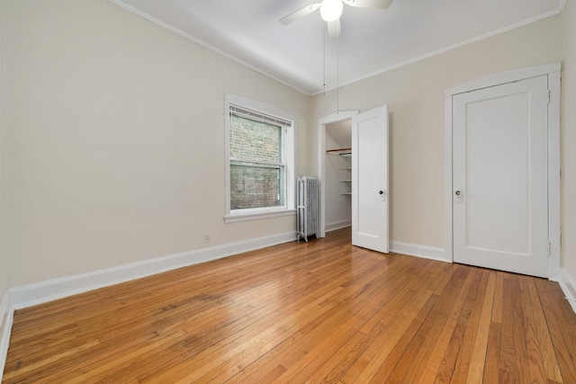 unfurnished bedroom featuring light hardwood / wood-style flooring, crown molding, radiator heating unit, and ceiling fan