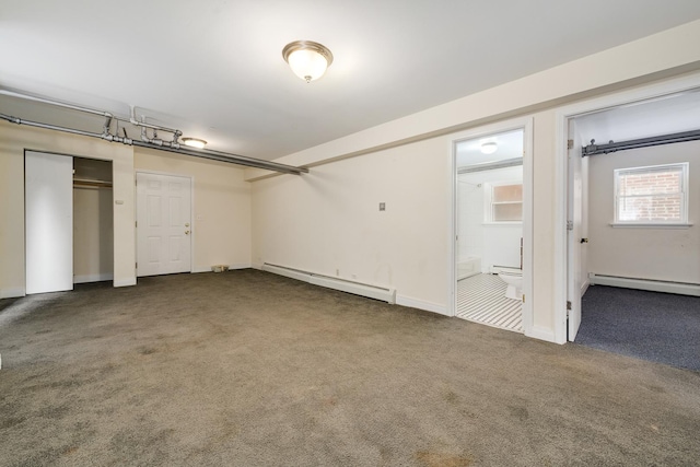 basement featuring a baseboard heating unit and carpet floors