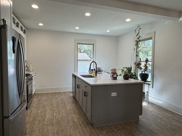 kitchen featuring sink, gray cabinetry, a kitchen island with sink, appliances with stainless steel finishes, and dark hardwood / wood-style flooring