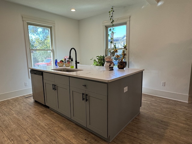 kitchen featuring an island with sink, hardwood / wood-style floors, gray cabinetry, sink, and dishwasher