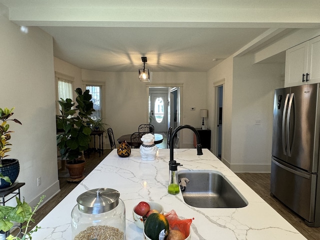 kitchen with stainless steel refrigerator, light stone counters, sink, dark hardwood / wood-style floors, and white cabinets