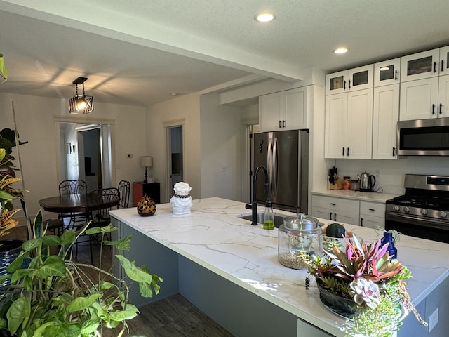 kitchen with stainless steel appliances, white cabinets, light stone counters, and dark hardwood / wood-style flooring