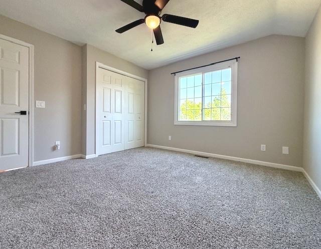2501 Woodridge Pl, Champaign, IL 61822 - unfurnished bedroom featuring carpet, a closet, baseboards, ceiling fan, and vaulted ceiling