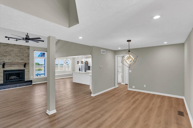 2501 Woodridge Pl, Champaign, IL 61822 - unfurnished living room with a chandelier, light wood-style flooring, baseboards, a stone fireplace, and recessed lighting