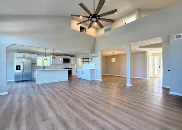 2501 Woodridge Pl, Champaign, IL 61822 - unfurnished living room with a ceiling fan, a high ceiling, baseboards, and wood finished floors