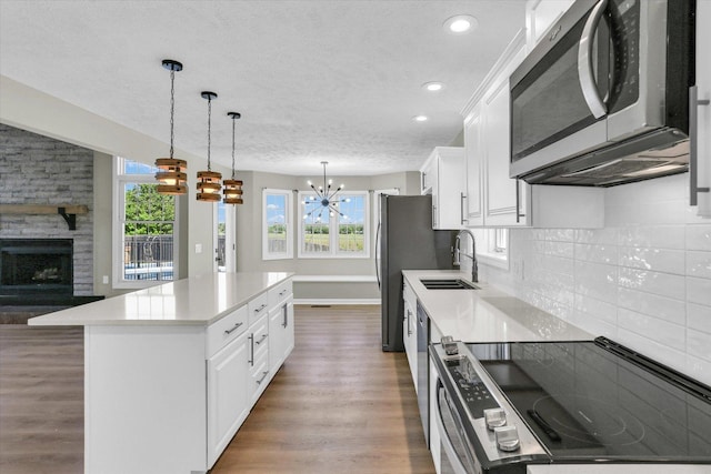 2501 Woodridge Pl, Champaign, IL 61822 - kitchen with stainless steel appliances, a sink, a chandelier, a textured ceiling, and wood finished floors