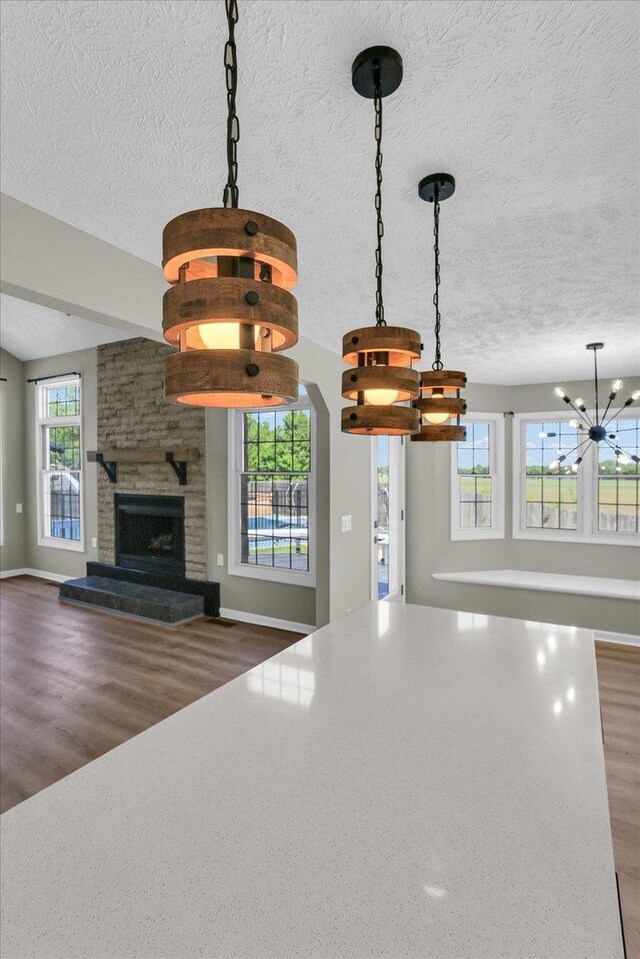 2501 Woodridge Pl, Champaign, IL 61822 - detailed view of a chandelier, a textured ceiling, wood finished floors, a fireplace, and baseboards