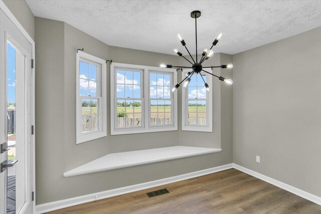 2501 Woodridge Pl, Champaign, IL 61822 - unfurnished dining area featuring a chandelier, wood finished floors, a textured ceiling, and baseboards