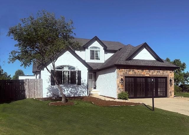 2501 Woodridge Pl, Champaign, IL 61822 - french provincial home with driveway, a garage, and stone siding
