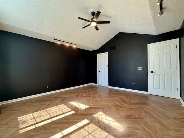 2501 Woodridge Pl, Champaign, IL 61822 - empty room with track lighting, baseboards, a textured ceiling, ceiling fan, and vaulted ceiling