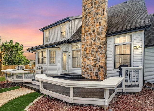 2501 Woodridge Pl, Champaign, IL 61822 - back of house at dusk with a chimney, a wooden deck, and roof with shingles