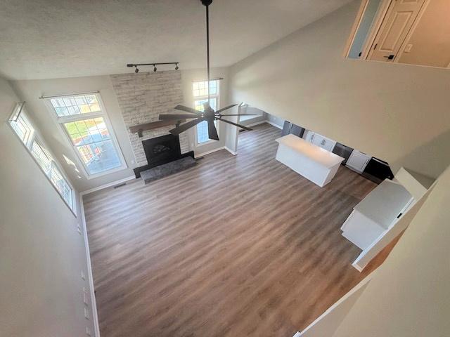 2501 Woodridge Pl, Champaign, IL 61822 - unfurnished living room featuring wood finished floors, rail lighting, baseboards, a ceiling fan, and a fireplace