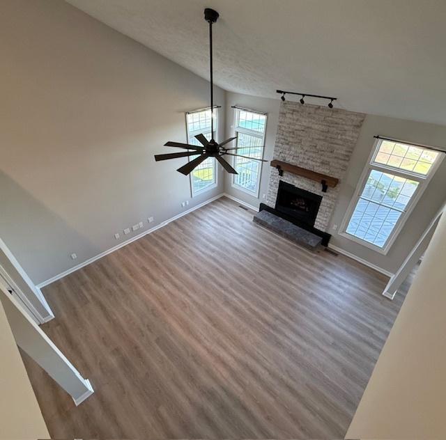 2501 Woodridge Pl, Champaign, IL 61822 - unfurnished living room featuring rail lighting, wood finished floors, baseboards, and vaulted ceiling