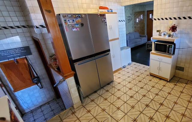 kitchen with stainless steel appliances, white cabinets, and tile walls