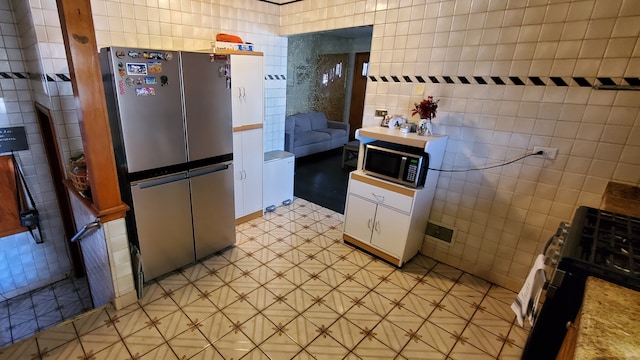 kitchen featuring white cabinetry, tile walls, and stainless steel appliances