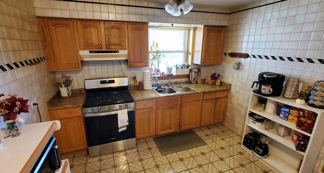 kitchen with stainless steel stove, sink, and tile walls