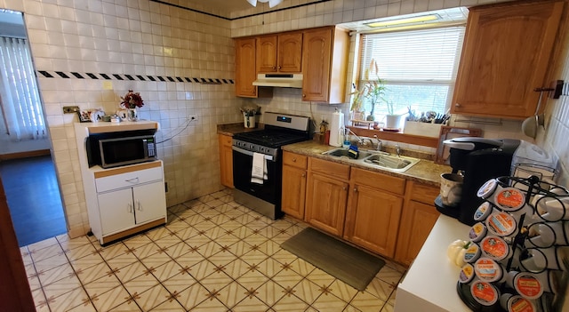 kitchen with stainless steel range, tile walls, and sink