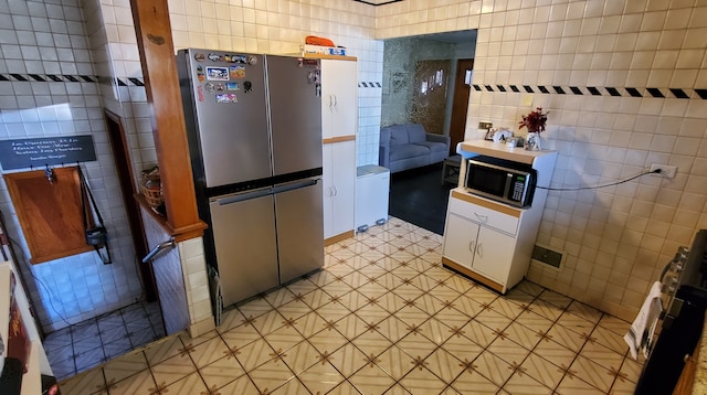 kitchen with white cabinets, tile walls, stainless steel fridge, and range