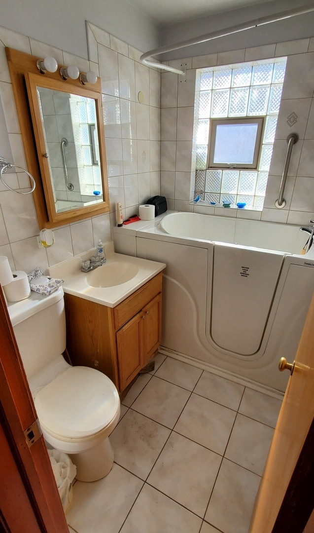 full bathroom featuring toilet, tile patterned floors, tile walls, backsplash, and vanity