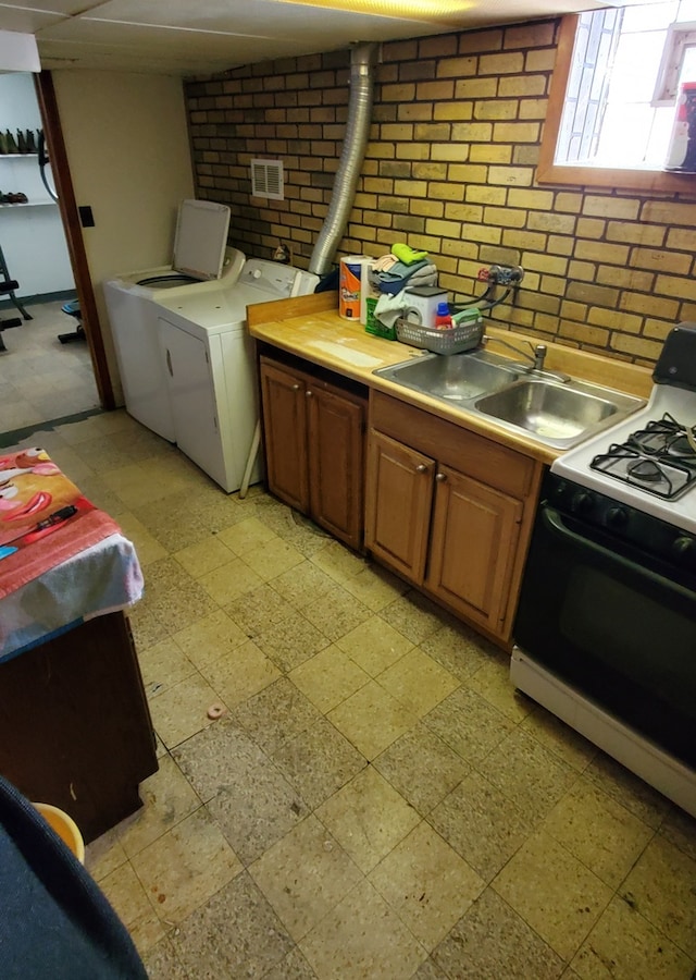 kitchen featuring washer and dryer, white range oven, sink, and decorative backsplash