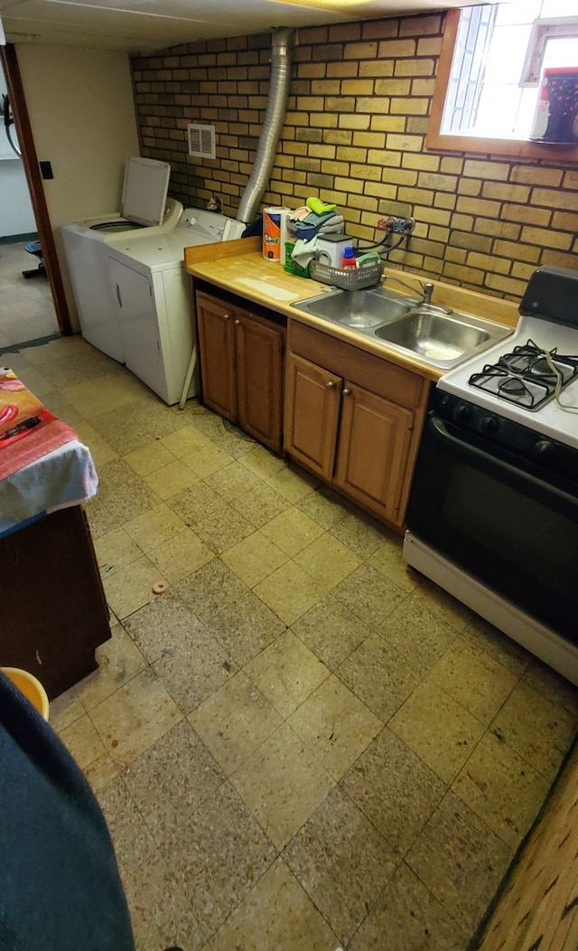 kitchen with decorative backsplash, sink, washing machine and clothes dryer, and white stove